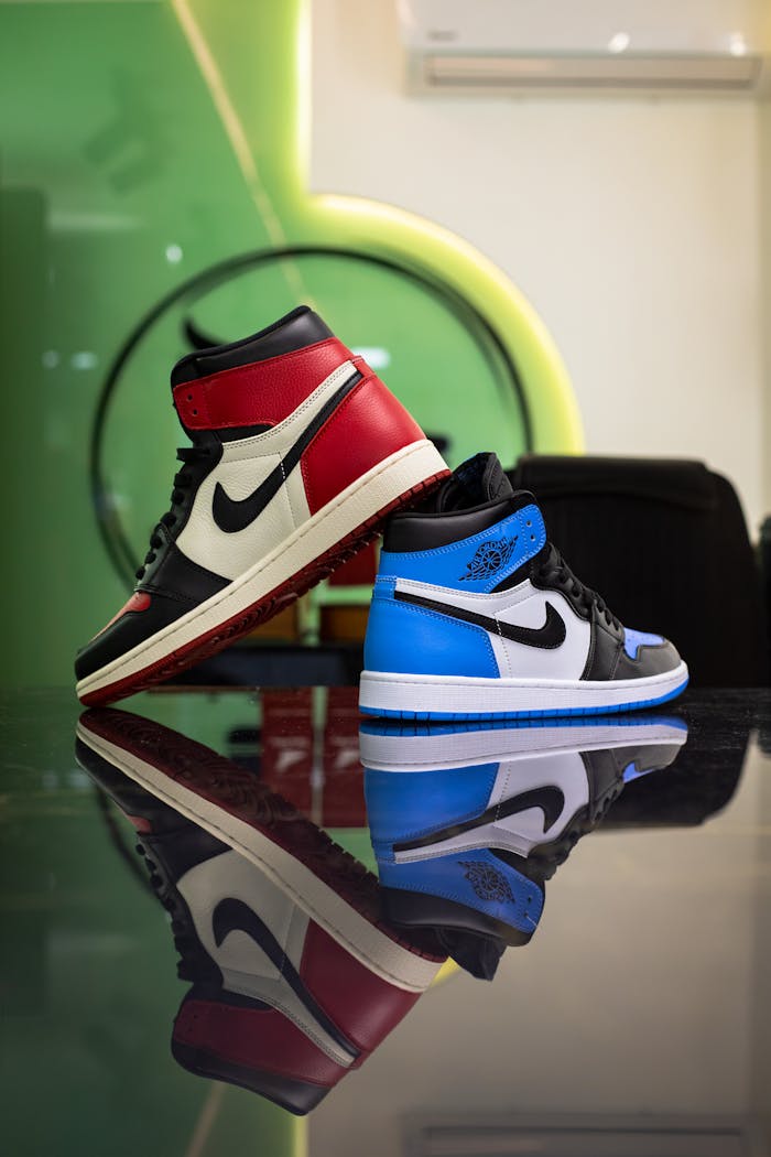 category-03 High-top sneakers in red and blue reflecting on glass indoors.