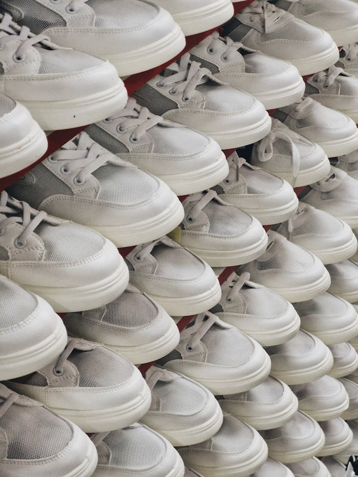 headline Rows of modern white sneakers neatly arranged, showcasing minimalist design in a retail setting.