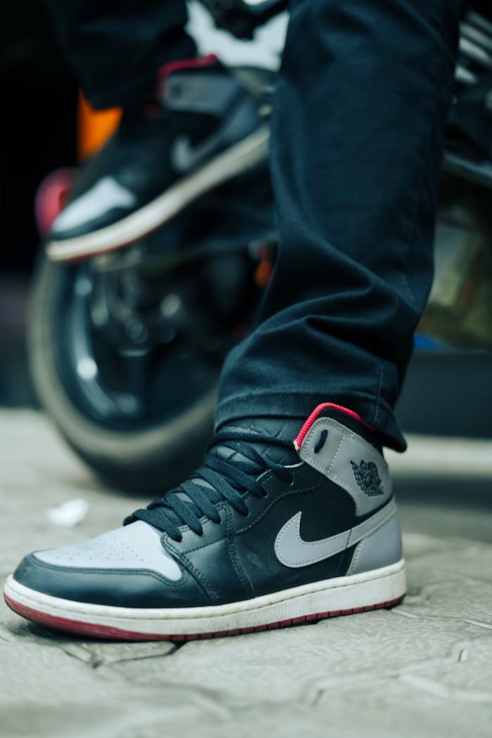 category-04 Focus on trendy sneakers with motorcycle in background on a street setting.